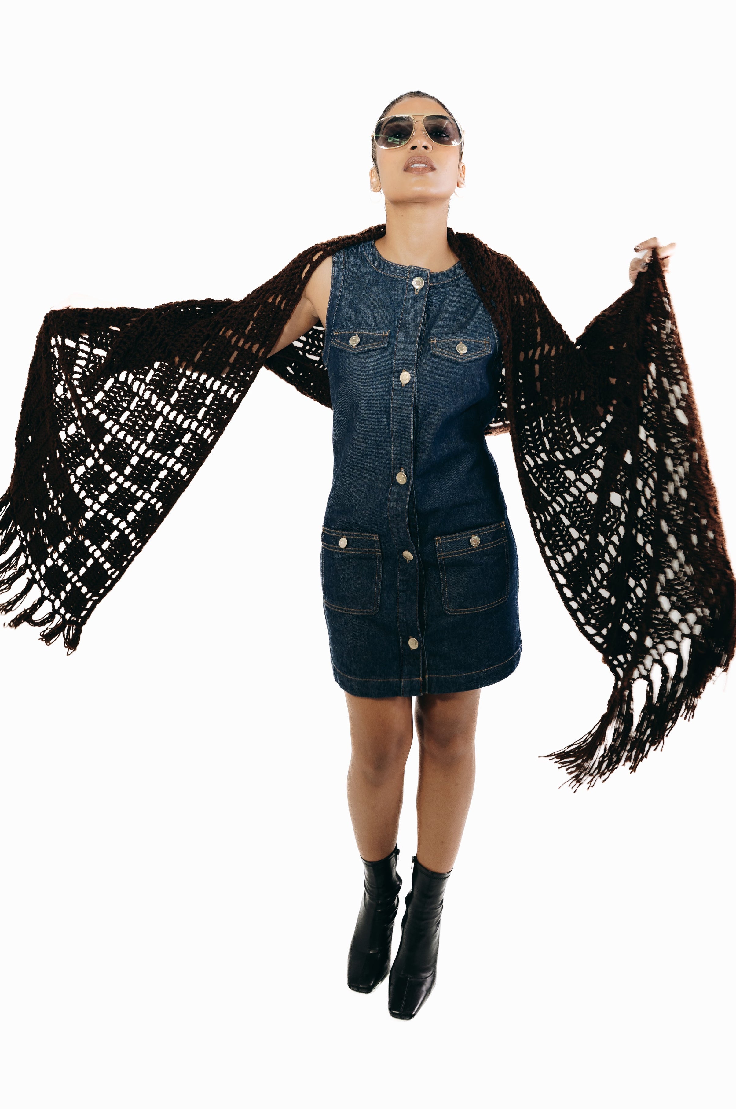 Woman wearing a denim dress with a black and white patterned shawl on a white background